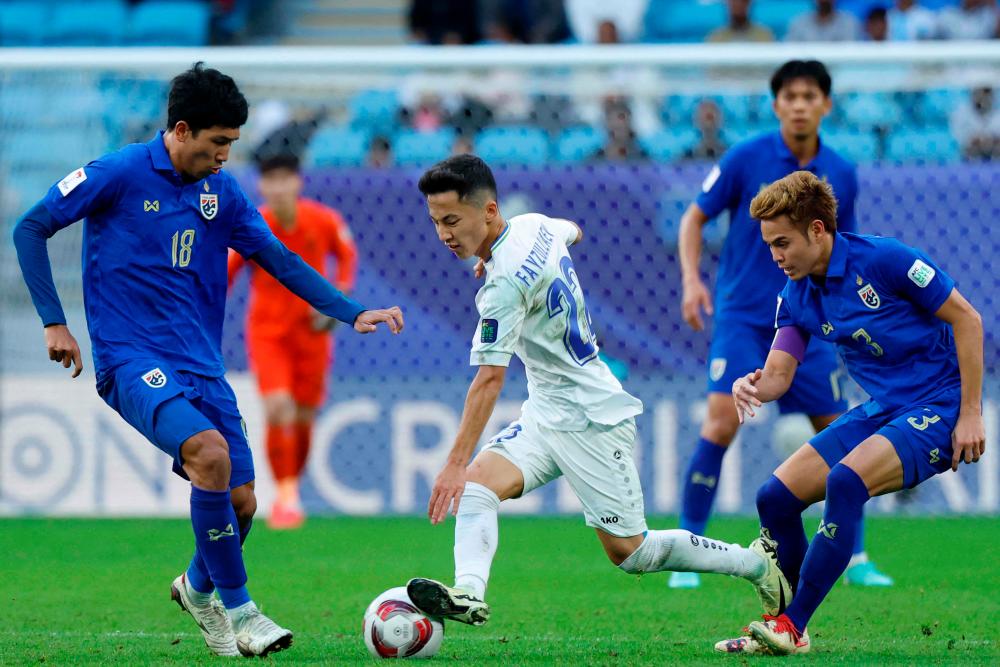 Uzbekistan’s midfielder #22 Abbosbek Fayzullaev is marked by Thailand’s midfielder #18 Weerathep Pomphan and Thailand’s defender #03 Theerathon Bunmathan during the Qatar 2023 AFC Asian Cup football match between Uzbekistan and Thailand at Al-Janoub Stadium in al-Wakrah, south of Doha, on January 30, 2024/AFPPix