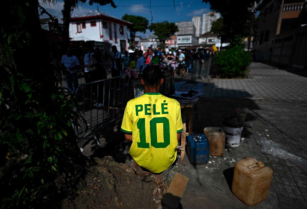 A man wears a jersey of Brazilian football legend Pele as people queue to get in the Urbano Caldeira stadium, also known as Vila Belmiro, where a wake in his honour is being held, in Santos, Sao Paulo State, Brazil, on January 2, 2023/AFPPix