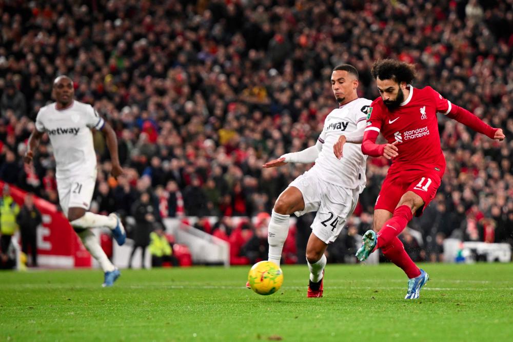 Liverpool's Egyptian striker #11 Mohamed Salah scores his team fourth goal during the English League Cup quarter-final football match between Liverpool and West Ham United at Anfield in Liverpool, north west England on December 20, 2023. - AFPPIX