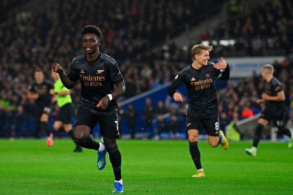 Arsenal’s English midfielder Bukayo Saka (L) celebrates after scoring the opening goal of the English Premier League football match between Brighton and Hove Albion and Arsenal at the American Express Community Stadium in Brighton, southern England on December 31, 2022/AFPPix