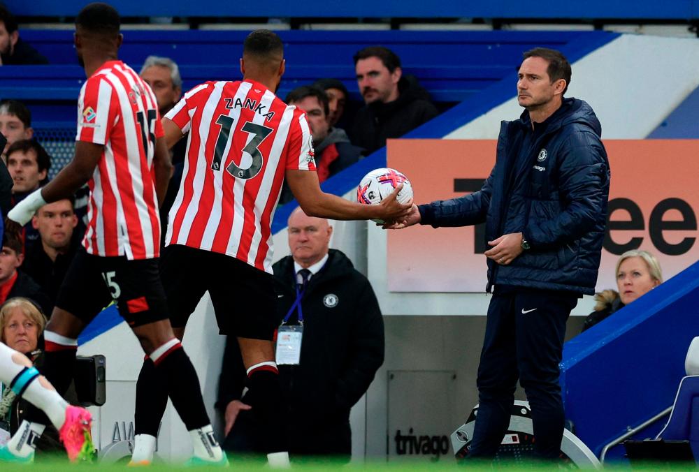 Chelsea's English caretaker manager Frank Lampard (R) passes a stray ball back to Brentford's Danish defender Mathias Jorgensen during the English Premier League football match between Chelsea and Brentford at Stamford Bridge in London on April 26, 2023. AFPPIX