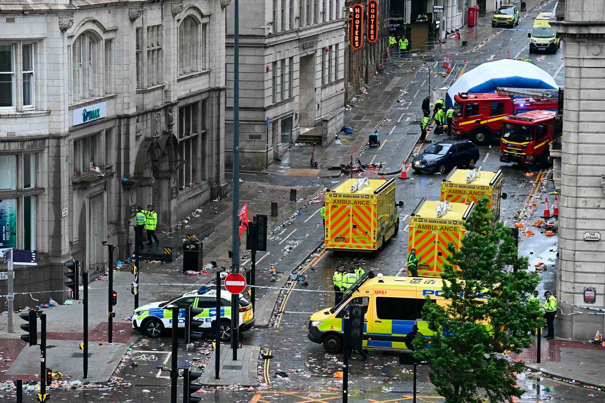 Police officers cover with an inflatable tent, behind a firefighter vehicle, the tents delimiting the scene of an incident in Water Street, on the sidelines of an open-top bus victory parade for Liverpool’s Premier League title win, in Liverpool, north-west England on May 26, 2025