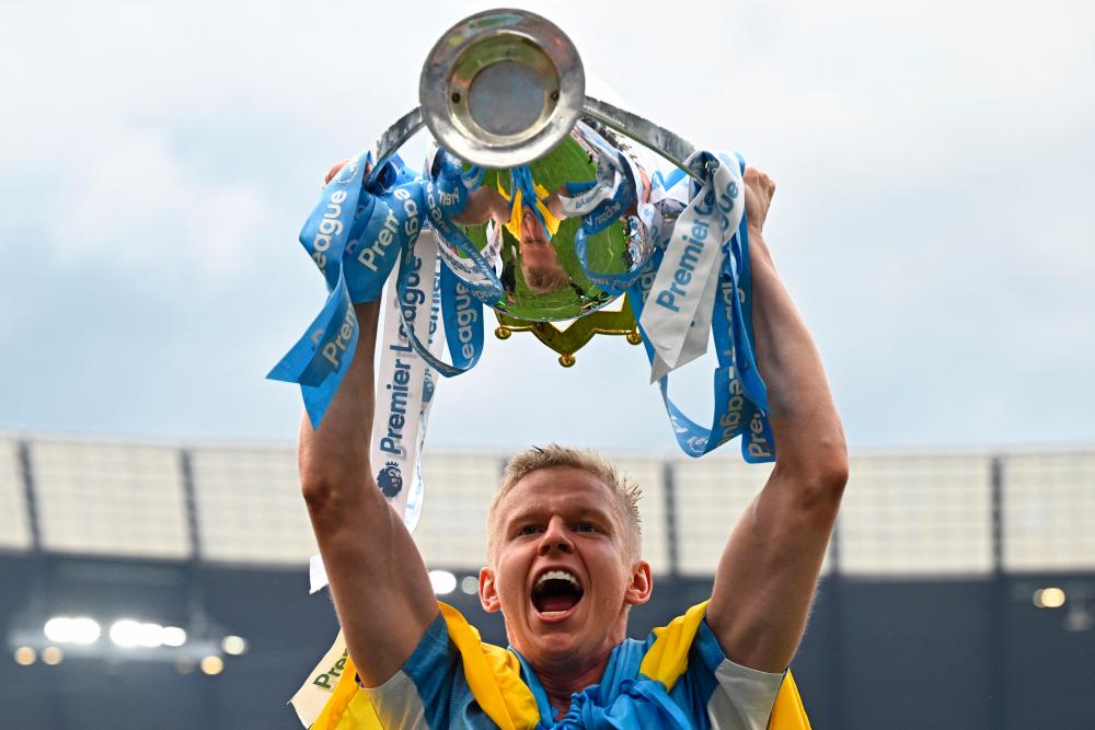 Manchester City’s Ukrainian midfielder Oleksandr Zinchenko celebrates with the Premier league trophy on the pitch after the English Premier League football match between Manchester City and Aston Villa at the Etihad Stadium in Manchester, north west England, on May 22, 2022. AFPPIX