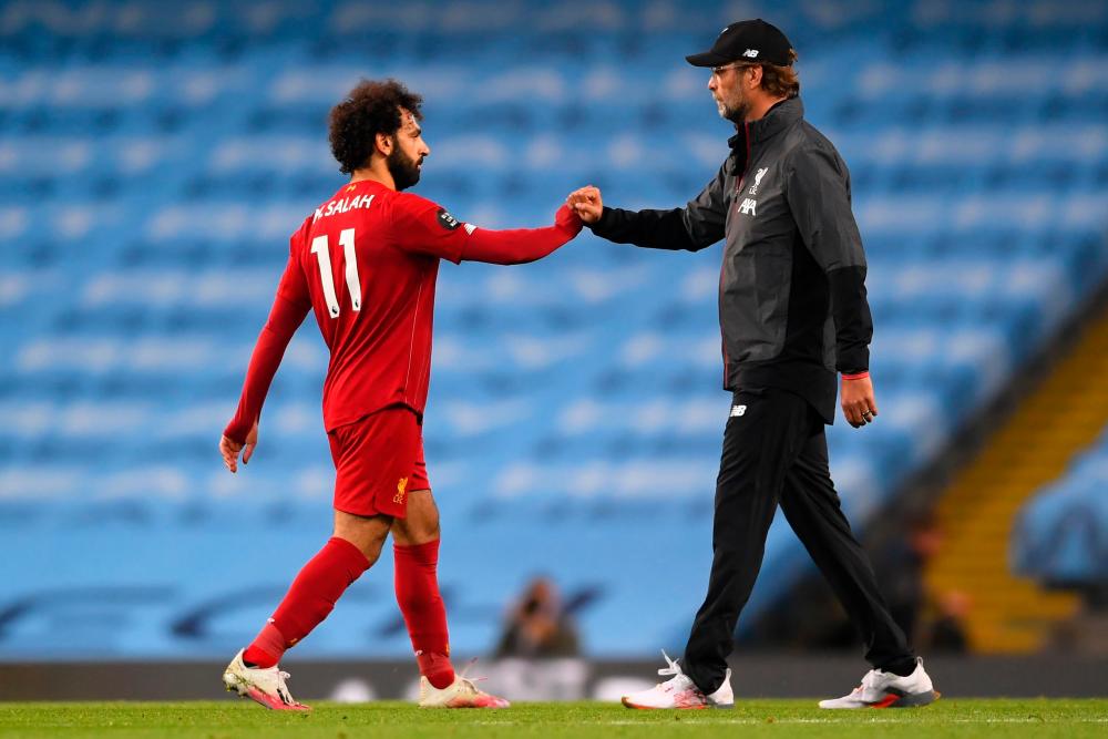 Liverpool’s German manager Jurgen Klopp and Liverpool’s Egyptian midfielder Mohamed Salah (L) on the pitch after the English Premier League football match between Manchester City and Liverpool at the Etihad Stadium in Manchester, north west England, on July 2, 2020. — AFP