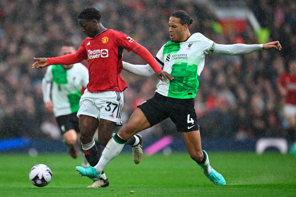Manchester United’s English midfielder #37 Kobbie Mainoo (L) vies with Liverpool’s Dutch defender #04 Virgil van Dijk (R) during the English Premier League football match between Manchester United and Liverpool at Old Trafford in Manchester, north west England, on April 7, 2024/AFPPix
