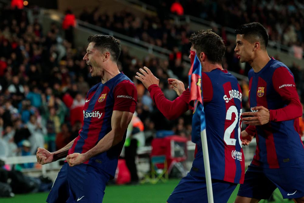 Barcelona's Polish forward #09 Robert Lewandowski celebrates with teammates after scoring his team's third goal during the Spanish league football match between FC Barcelona and Valencia CF at the Estadi Olimpic Lluis Companys in Barcelona on April 29, 2024. - AFPPIX