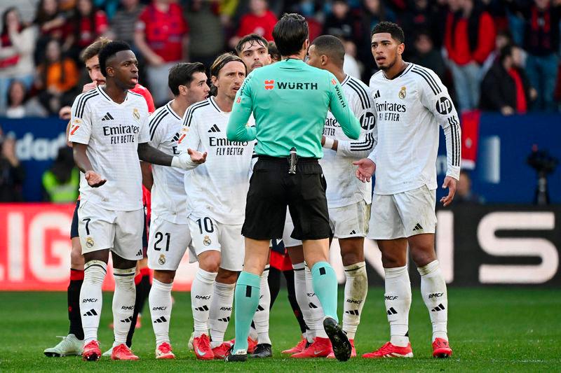 Real Madrid's players remonstrate with Spanish referee Munuera Montero about the red card presented to Real Madrid's English midfielder #05 Jude Bellingham (R) during the Spanish league football match between CA Osasuna and Real Madrid CF at El Sadar Stadium in Pamplona on February 15, 2025. - AFPPIX