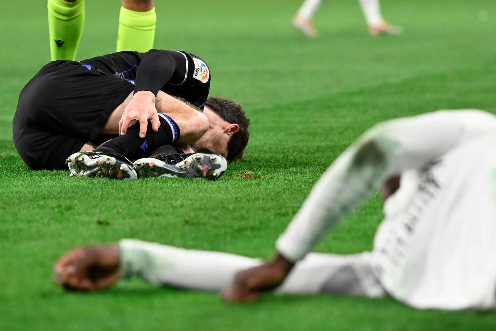 Real Sociedad's Spanish defender Aritz Elustondo (L) lies on the field after tackling Real Madrid's French midfielder Eduardo Camavinga (R) during the Spanish league football match between Real Madrid CF and Real Sociedad at the Santiago Bernabeu stadium in Madrid on January 29, 2023. AFPPIX