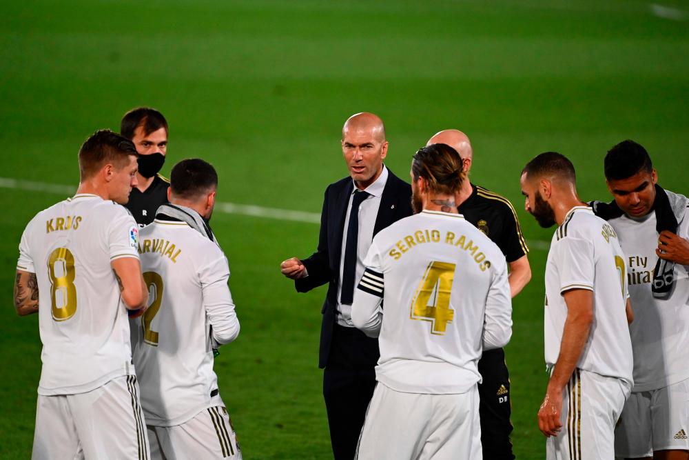 Real Madrid’s French coach Zinedine Zidane (C) talks to his players during the Spanish league football match Real Madrid CF againsrt Getafe CF at the Alfredo di Stefano stadium in Valdebebas, on the outskirts of Madrid, on July 2, 2020. — AFP