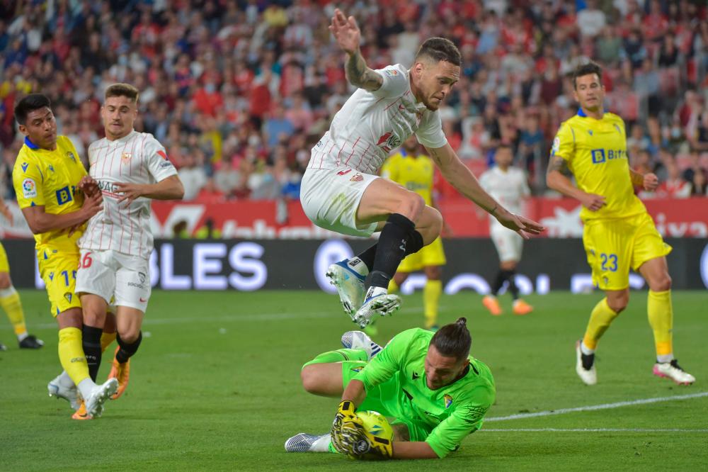 Sevilla’s Argentinian midfielder Lucas Ocampos jumps over Cadiz’s Argentinian goalkeeper Jeremias Ledesma during the Spanish League football match between Sevilla FC and Cadiz CF at the Ramon Sanchez Pizjuan stadium in Seville on April 29, 2022. AFPPIX
