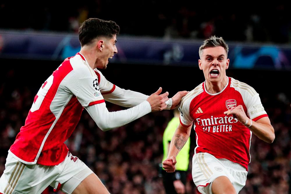 Arsenal's Belgian midfielder #19 Leandro Trossard (R) celebrates after scoring his team second goal during the UEFA Champions League quarter final first-leg football match between Arsenal and Bayern Munich at the Arsenal Stadium, in north London, on April 9, 2024. - AFPPIX