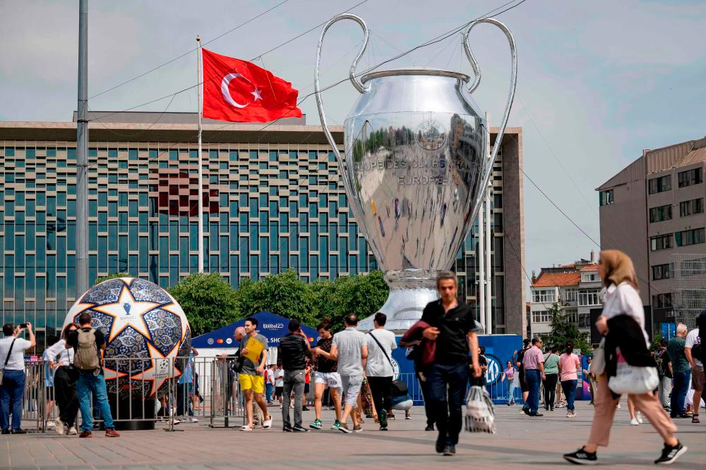 Pedestrians walk an inflatable model of the UEFA Champions League trophy on Taksim Square in Istanbul, on June 2023. AFPPIX