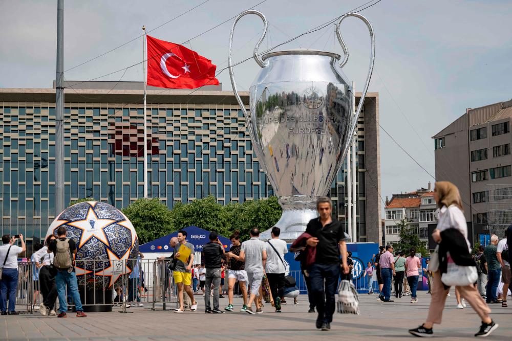 Pedestrians walk an inflatable model of the UEFA Champions League trophy on Taksim Square in Istanbul, on June 2023. AFPPIX