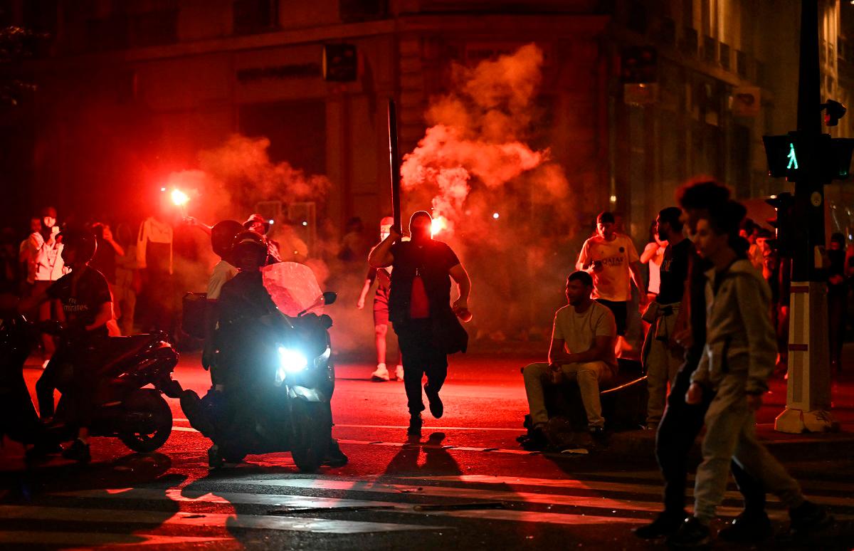 PSG supporters gather holding flares on a street in Paris early June 1, 2025, during celebrations following their 5-0 victory in the UEFA Champions League final football match between Paris Saint-Germain (PSG) and Inter Milan held in Munich. - LOU BENOIST / AFP