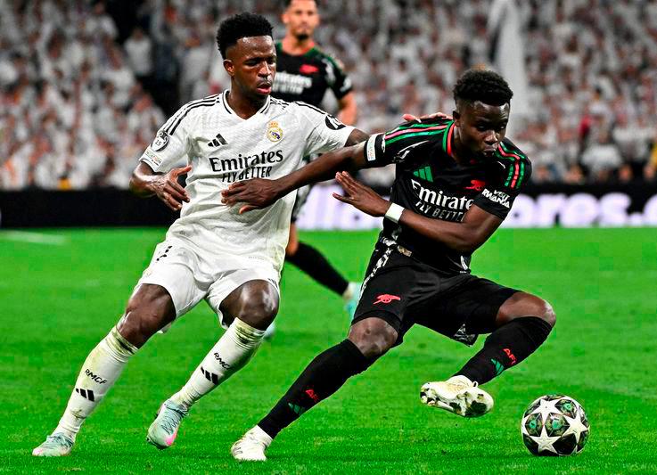 Real Madrid’s Brazilian forward #07 Vinicius Junior fights for the ball with Arsenal’s English midfielder #07 Bukayo Saka during the UEFA Champions League quarter final second leg football match between Real Madrid CF and Arsenal at Santiago Bernabeu Stadium in Madrid on April 16, 2025. - AFPPIX