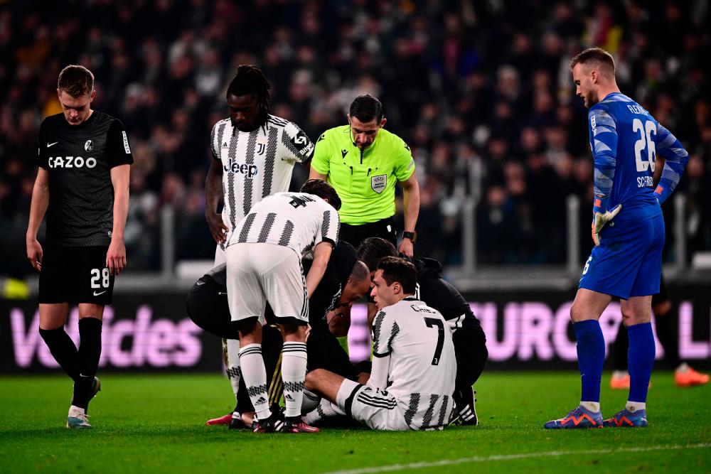 Greek referee Tasos Sidiropoulos, SC Freiburg’s German defender Matthias Ginter (L), Juventus’ Italian forward Moise Kean (2ndL) and SC Freiburg’s Dutch goalkeeper Mark Flekken (R) stand by as medics tend to Juventus’ Italian forward Federico Chiesa (Bottom) during the UEFA Europa League round of 16 first leg football match between Juventus and SC Freiburg on March 9, 2023 at the Juventus stadium in Turin/AFPPix