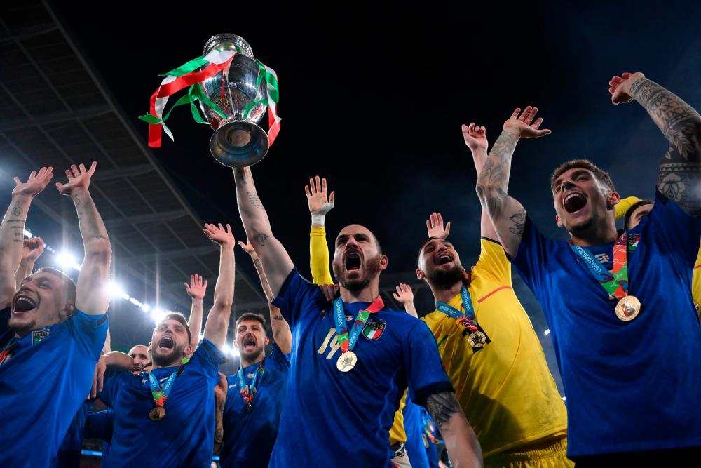 Italy's defender Leonardo Bonucci (C) poses with the European Championship trophy after Italy won the UEFA EURO 2020 final football match between Italy and England at the Wembley Stadium in London on July 11, 2021. – AFP