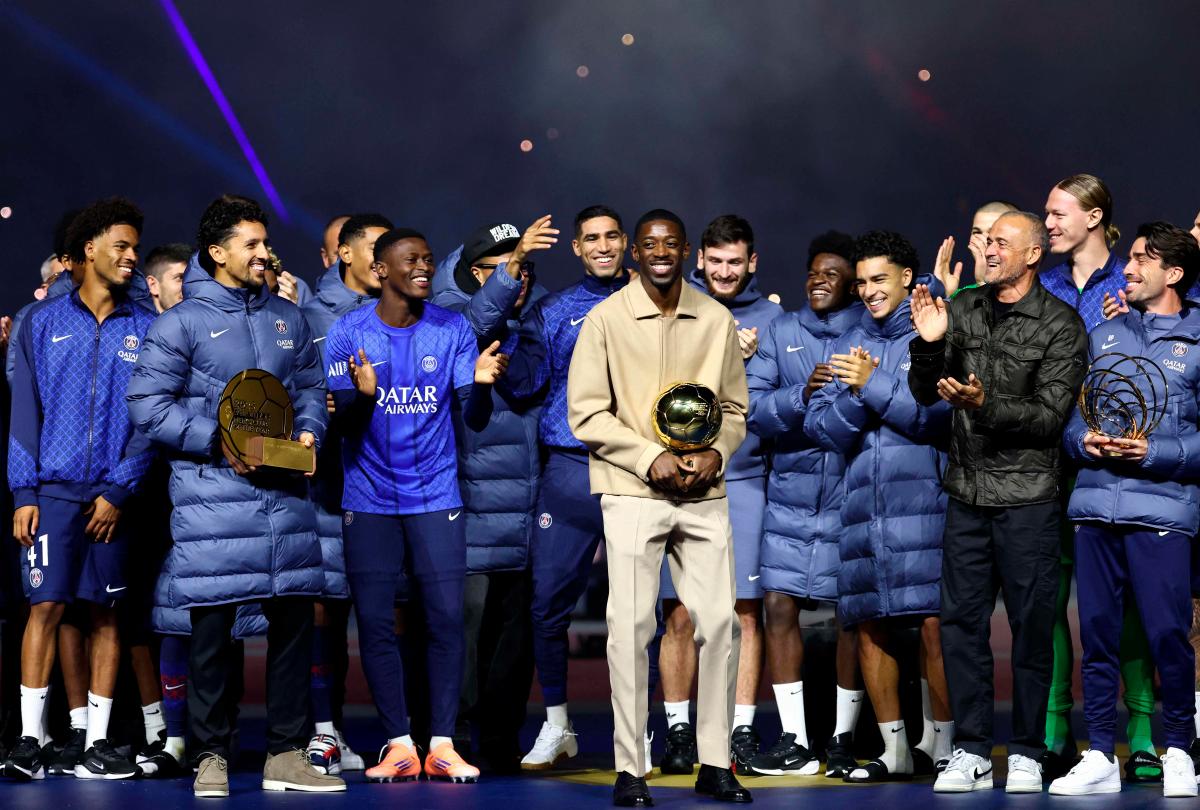 Paris Saint-Germain’s French forward #10 Ousmane Dembele (C) celebrates with the Ballon d’Or trophy and his teammates during a ceremony after the French L1 football match between Paris Saint-Germain (PSG) and Auxerre at the Parc des Princes stadium in Paris on September 27, 2025. (Photo by FRANCK FIFE / POOL / AFP)