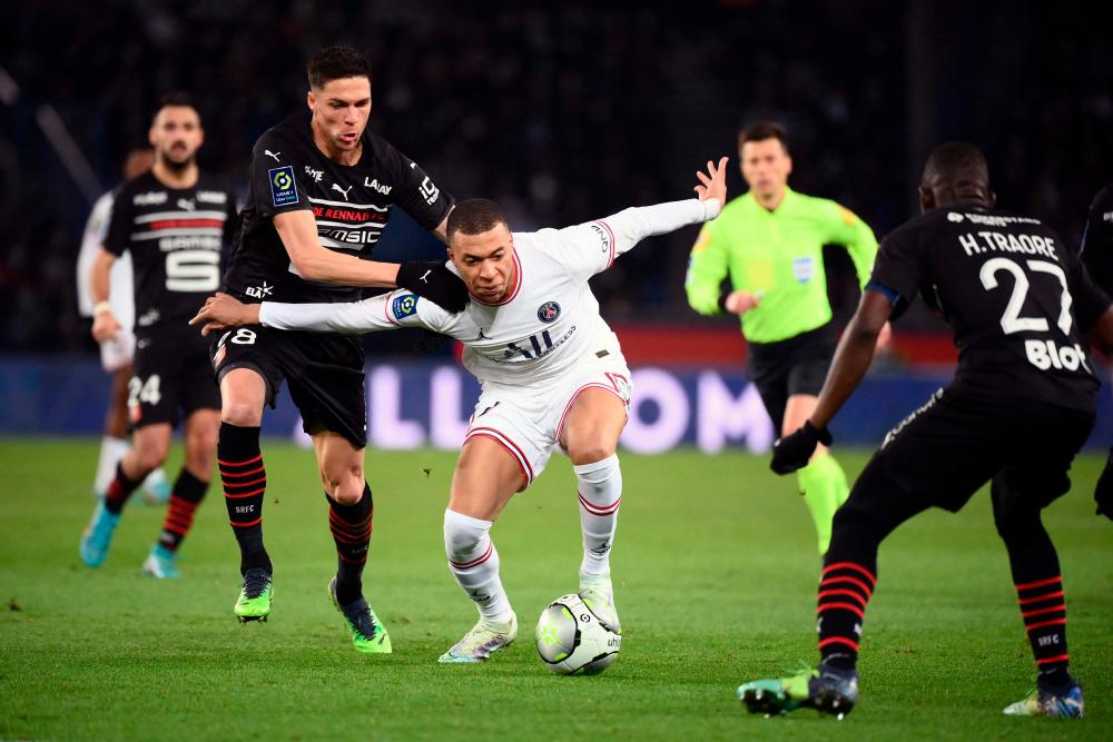 Rennes’ French midfielder Jonas Martin and Paris Saint-Germain’s French forward Kylian Mbappe (C) fight for the ball during the French L1 football match between Paris-Saint Germain (PSG) and Le Stade rennais Football Club at The Parc des Princes Stadium in Paris on February 11, 2022. AFPPIX