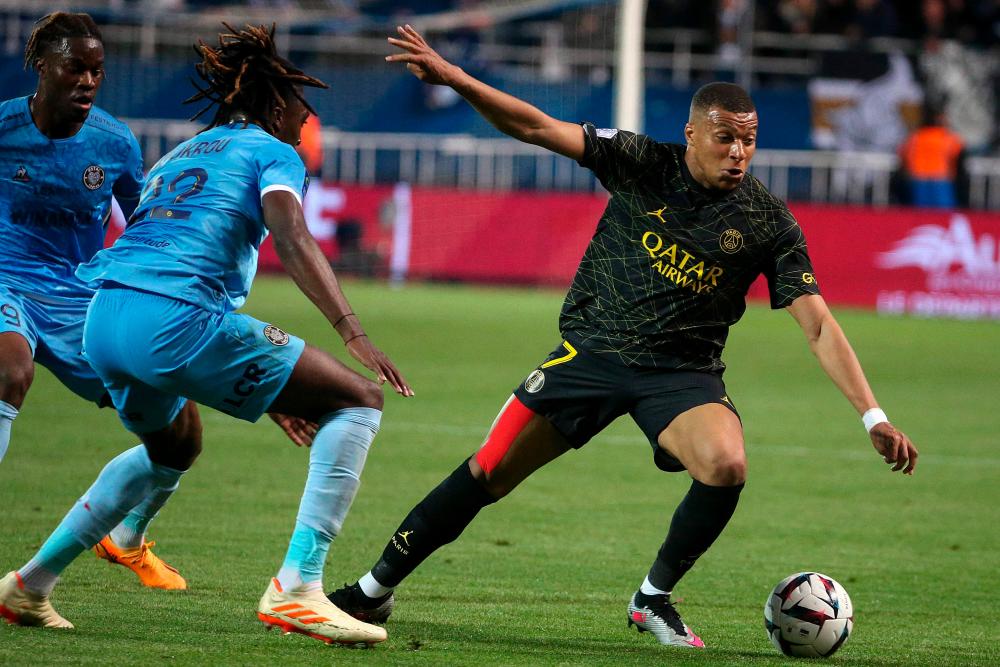 Kylian Mbappe (R) fights for the ball with Troyes' French defender Tanguy Zoukrou (L) during the match between ES Troyes AC and Paris Saint-Germain (PSG) at Stade de l'Aube in Troyes, north-eastern France on May 7, 2023. AFPPIX