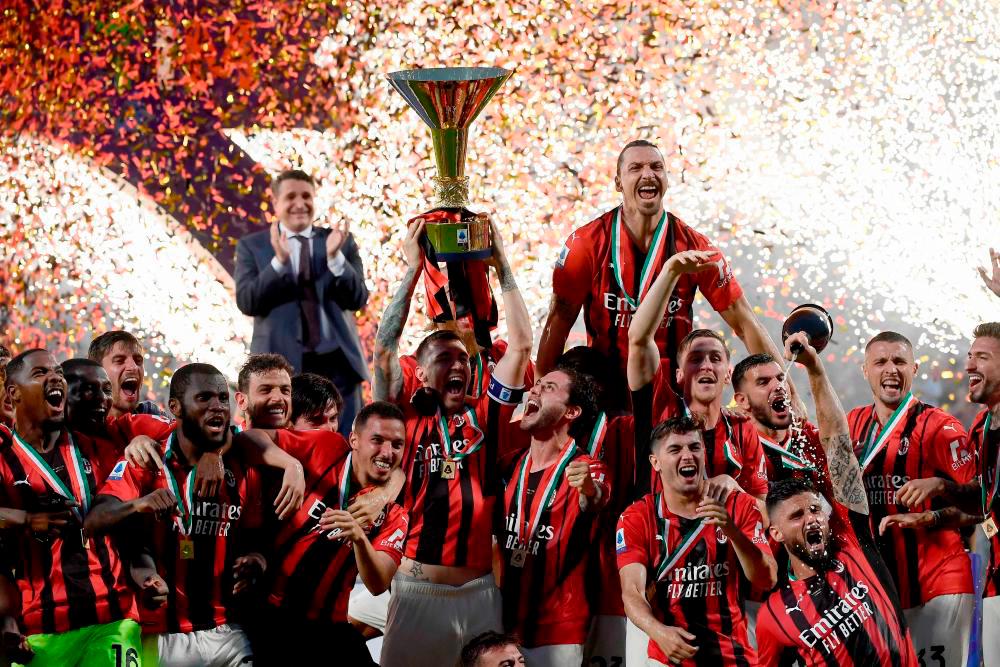 AC Milan’s Italian defender Alessio Romagnoli (C-L with throphy), AC Milan’s Swedish forward Zlatan Ibrahimovic (Top R), AC Milan’s French forward Olivier Giroud (Bottom R) and AC Milan’s players celebrate with the winner’s trophy after AC Milan won the Italian Serie A football match between Sassuolo and AC Milan, securing the “Scudetto” championship on May 22, 2022. AFPPIX
