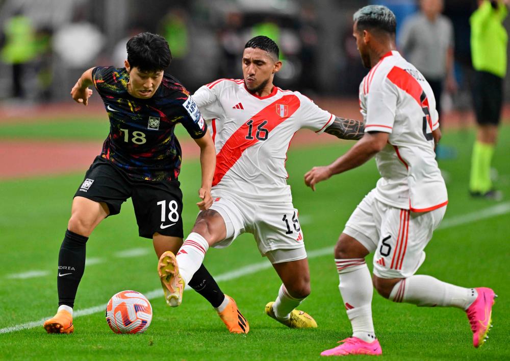 South Korea’s Lee Kang-in (L) fights for the ball with Peru’s Christofer Gonzales (C) during the friendly football match between South Korea and Peru at Busan Asiad Stadium in Busan on June 16, 2023/AFPPix