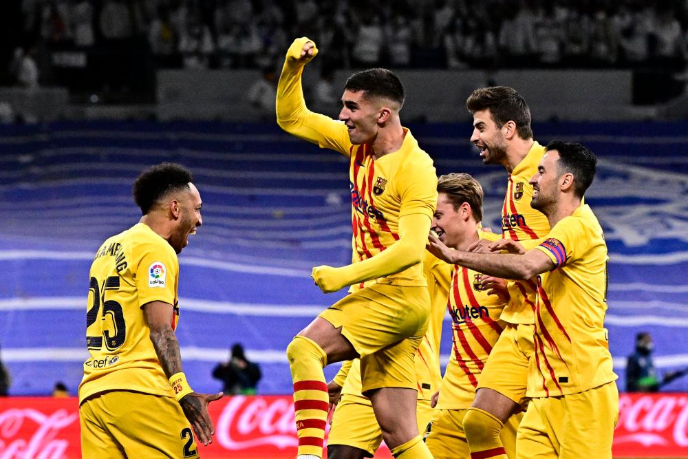 Barcelona’s Gabonese midfielder Pierre-Emerick Aubameyang (L) celebrates with teammates after scoring a goal during the Spanish League football match between Real Madrid CF and FC Barcelona at the Santiago Bernabeu stadium in Madrid on March 20, 2022. AFPPIX
