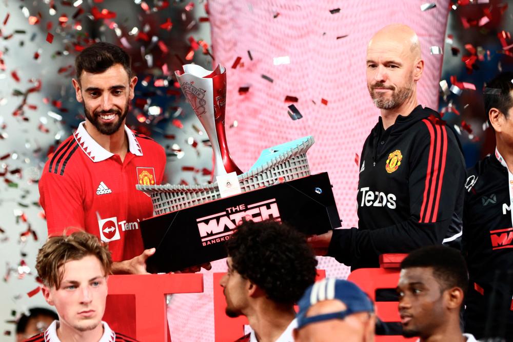 Manchester United manager Erik Ten Hag (right) and midfielder Bruno Fernandes (left) hold a trophy after the exhibition match against Liverpool at Rajamangala National Stadium in Bangkok on July 12, 2022. – AFPPIX