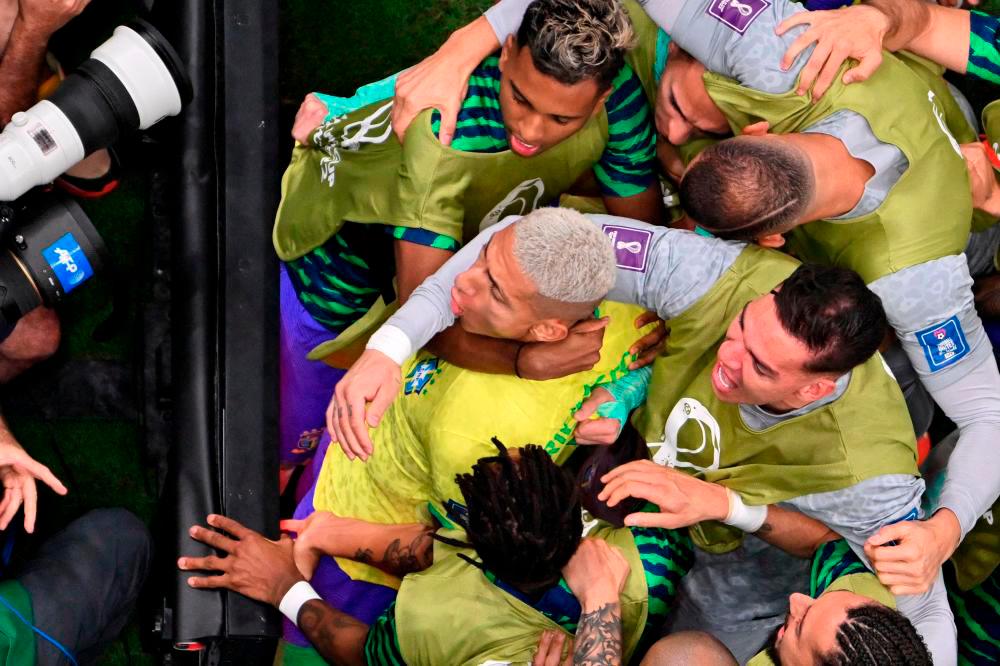 Richarlison (C) celebrates with teammates after scoring his team’s first goal. AFPPIX