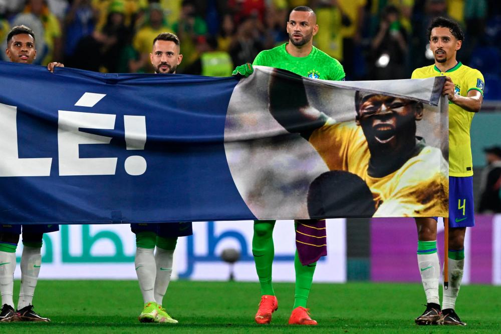 Brazil's forward #21 Rodrygo, Brazil's midfielder #22 Everton Ribeiro, Brazil's goalkeeper #12 Weverton and Brazil's defender #04 Marquinhos hold a banner depicting Brazilian football superstar Pele as he celebrates after qualifying to the next round after defeating South Korea 4-1 in the Qatar 2022 World Cup round of 16 football match between Brazil and South Korea at Stadium 974 in Doha on December 5, 2022. (Photo by Pablo PORCIUNCULA / AFP)