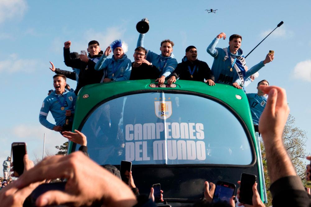 Uruguay’s players celebrate on board a bus during a victory parade in Montevideo on June 12, 2023, a day after Uruguay won the country’s first Under-20 World Cup title after defeating Italy 1-0 in the final/AFPPix
