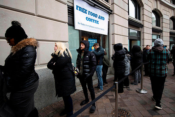Federal workers stay in line for a free hot meal at Andres in Washington, DC, as the restaurant reached out to locals providing ready-to-eat meals for federal families affected by the US government shutdown. — AFP