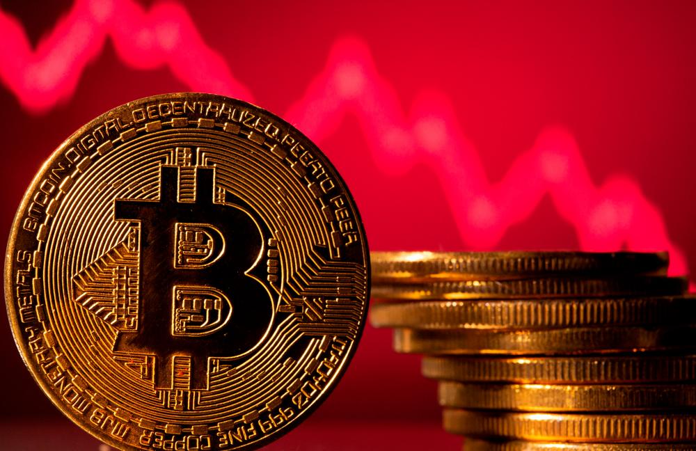 A representation of bitcoin is seen in front of a stock graph in this illustration. – Reuterspic