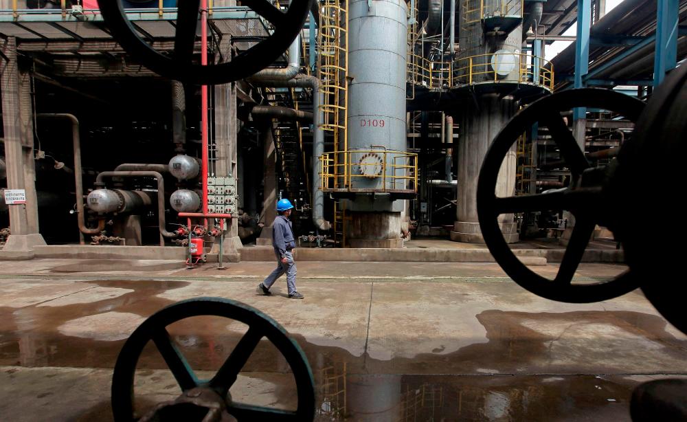 File picture of a worker walking past oil pipes at a refinery in Wuhan, China. – Reuterspic