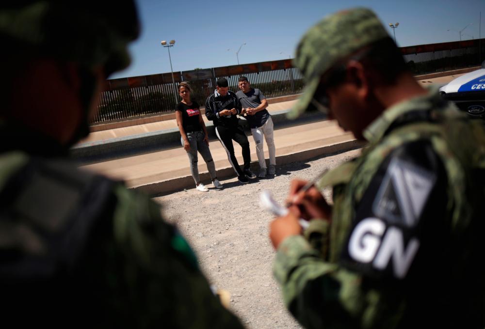 Members of Mexico's National Guard detain Cuban migrants after they were trying to cross illegally the border between the US and Mexico, in Ciudad Juarez, Mexico June 21, 2019. - Reuters