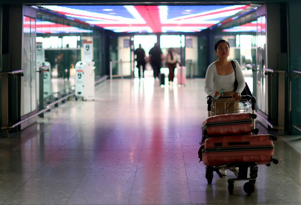FILE PHOTO: A passengers walks with her luggage through Heathrow Terminal 5 airport in London, Britain, June 1, 2022. - REUTERSPIX
