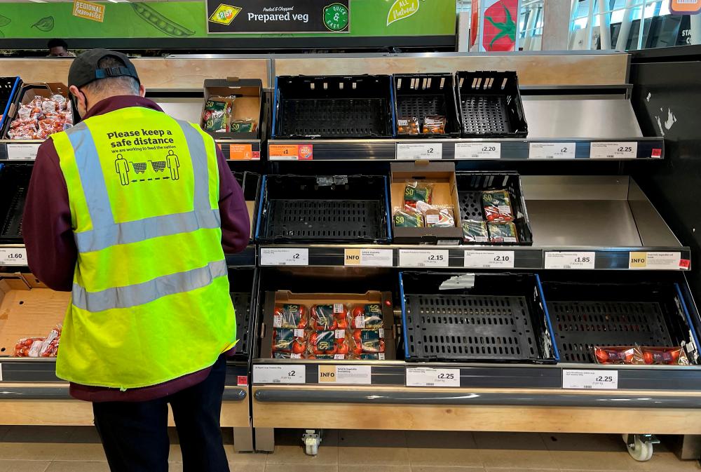 An employee checking stock levels at the fruit and vegetable aisle at a supermarket in Londonin February. Official data shows the UK economy narrowly avoided a recession after zero growth in the final quarter of 2022 .– Reuterspic