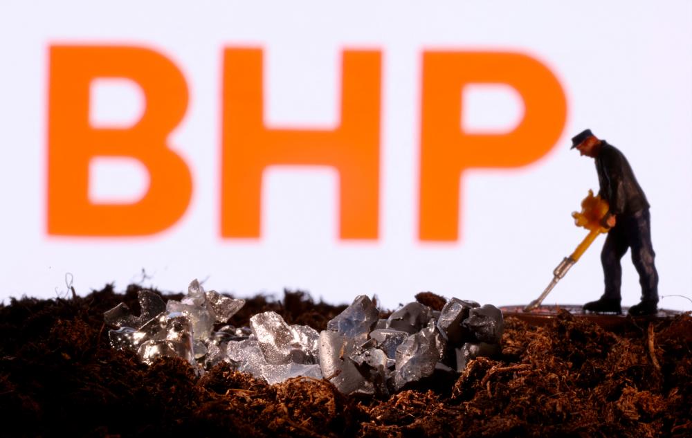 A small toy figure and imitation minerals are seen in front of the BHP logo in this illustration. – Reuterspic