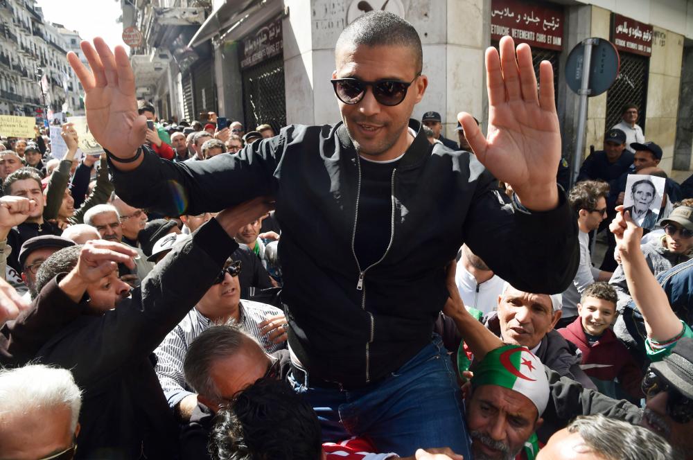 This file photo taken on March 6, 2020 shows Algerian journalist Khaled Drareni gesturing while being carried by protesters on their shoulders after he was briefly detained by security forces in the Algerian capital Algiers. — AFP