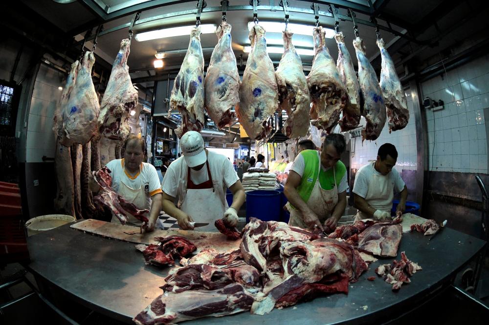 (FILES) In this file photo taken on February 18, 2016, workers cut up beef in a butcher's shop in Buenos Aires. – AFP