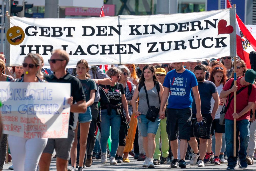 (FILES) In this file photo taken on September 11, 2021 Demonstrators hold a banner reading “Give the children their laughter back” during a protest against the governmental coronavirus Covid-19 pandemic measures, in Vienna, on September 11, 2021.AFPpix