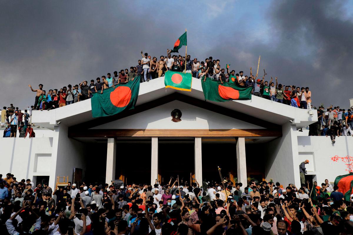 Anti-government protestors display Bangladesh’s national flag as they storm Prime Minister Sheikh Hasina’s palace in Dhaka on August 5, 2024. - AFPPIX