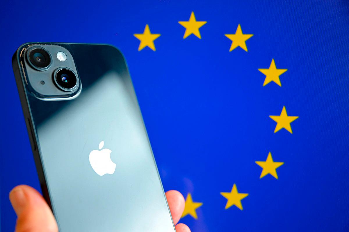 (FILES) This photograph shows a hand-held smartphone with the Apple company logo and the European Union logo in the background, in Brussels. - Nicolas TUCAT / AFP