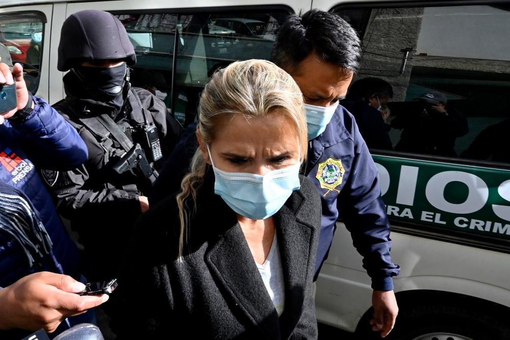 (FILES) In this file photo taken on March 13, 2021 Former interim Bolivia’s President Jeanine Anez (C) is escorted by police members of the Special Force against Crime (FELCC) after being arrested in La Paz. AFPPIX