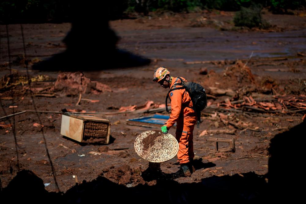 Firefighter captain Leonard Farah rescues personal belongings from houses destroyed by the mudslide, one month after the rupture of a tailings dam of mining company Vale in Corrego do Feijao, near Brumadinho, in the Brazilian state of Minas Gerais, on February 22, 2019/AFPPix