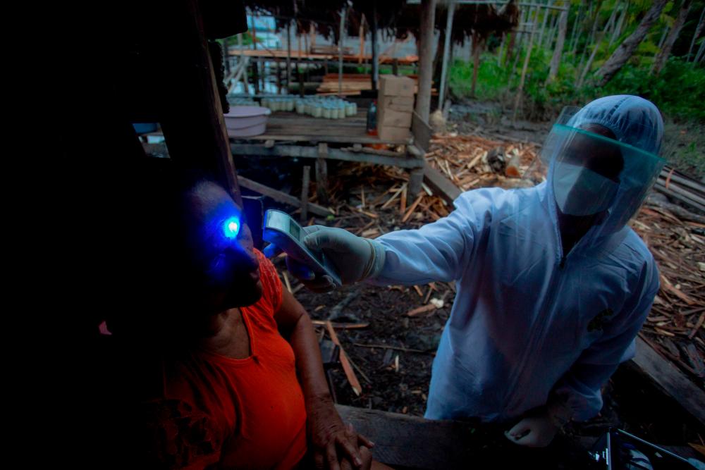 In this file photo taken on June 09, 2020 health workers from the city of Melgaco check a woman with Covid-19 symptoms at a small riverside community in the southwest of Marajo Island, state of Para, Brazil. — AFP
