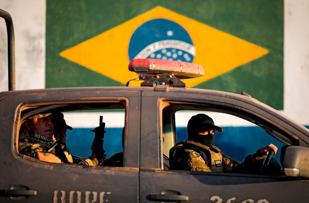 (FILES) In this file photo taken on June 20, 2021, police officers take part in an operation to capture Lazaro Barbosa, suspected of serial murders, in Cocalzinho de Goias, Brazil. – AFP