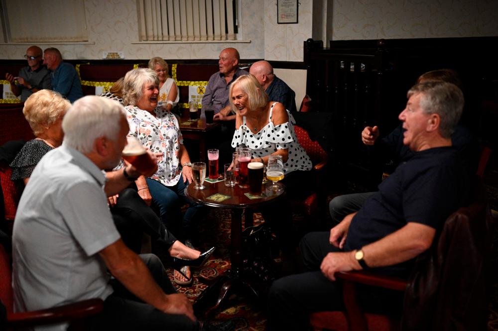 In this photo taken on July 4, 2020 people enjoy a drink with yellow tape on the seats aiding social distancing inside the Burnley Miners Working Men's Social Club in Burnley, north-west England, as restrictions are further eased during the coronavirus COVID-19 pandemic. – AFP