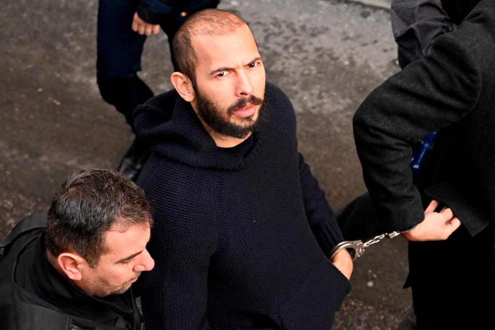 In this file photo taken on February 01, 2023 British-US influencer Andrew Tate arrives handcuffed and escorted by police at a courthouse in Bucharest on February 1, 2023 to hear the court decision on his appeal against pre-trial detention for alleged human trafficking, rape and forming a criminal group. AFPPIX