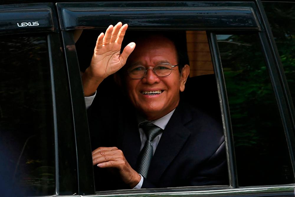 (FILES) In this file photo taken on October 19, 2022 Kem Sokha, former leader of the now-dissolved Cambodia National Rescue Party (CNRP), greets people as he leaves the Phnom Penh Municipal Court after attending his treason trial in Phnom Penh. AFPPIX
